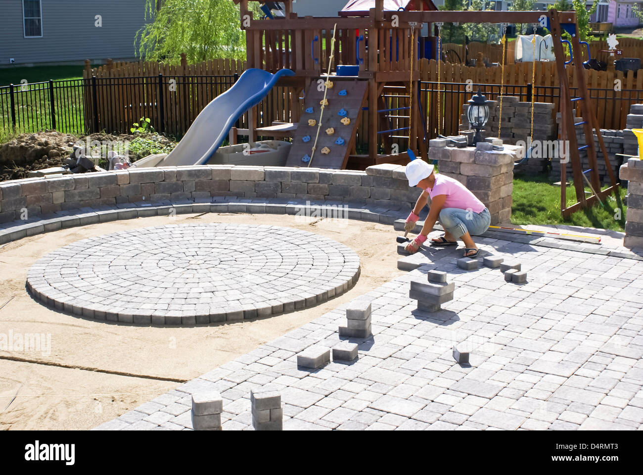 Frau mit dem weißen Hut Terrasse im Hinterhof ihres Hauses zu ebnen. Stockfoto