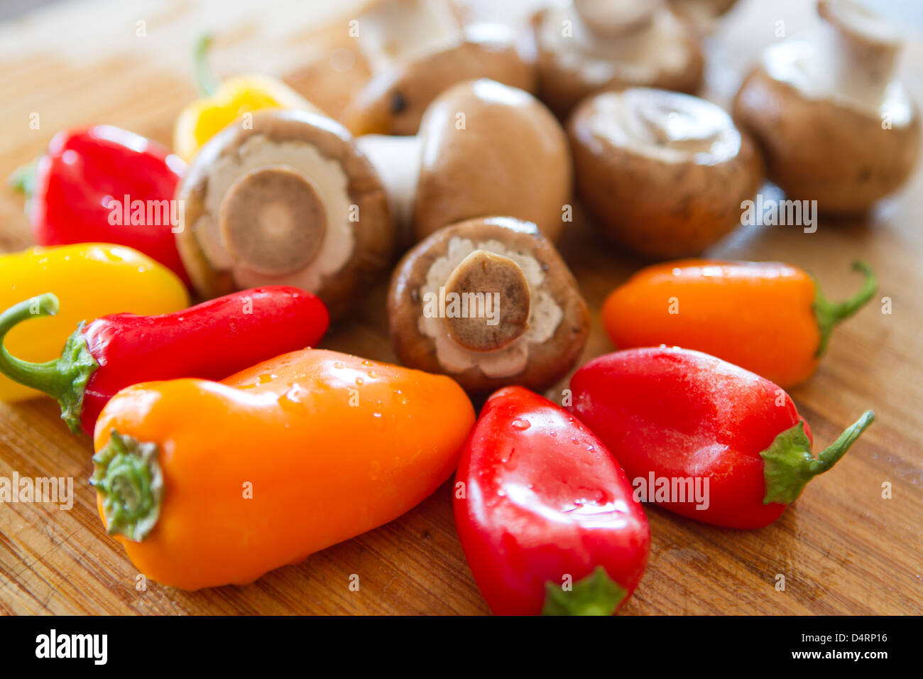 Pilze und bunte Paprika erhalten momentan auf einem nassen Bambus Schneidbrett schneidet nachdem sie ihre Dusche zu nehmen. Stockfoto