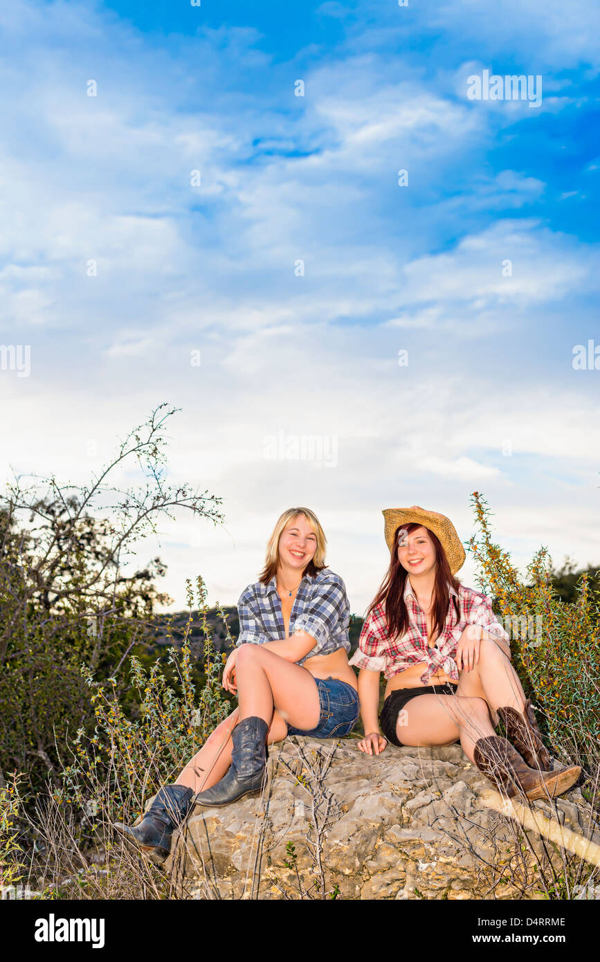 Freunde - zwei weibliche Teenager im Land Mädchen Kleidung sitzt auf einem Felsen, Weibchen 19 Caucasion, Texas, USA Stockfoto