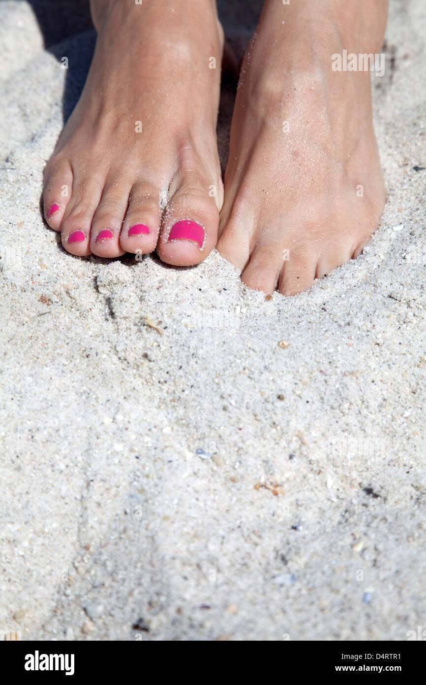 Füße im Sand mit rosa Fußnägel, einen Fuß in den Sand zu graben. Stockfoto