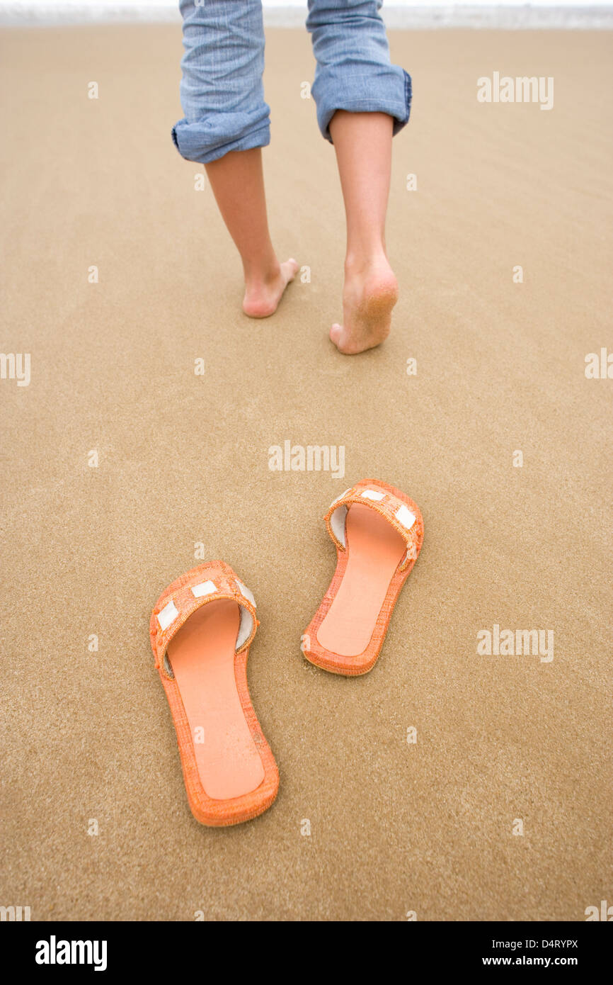 Teenager-Mädchen zu Fuß in Richtung Meer mit Sandalen, die am Strand liegen  Stockfotografie - Alamy