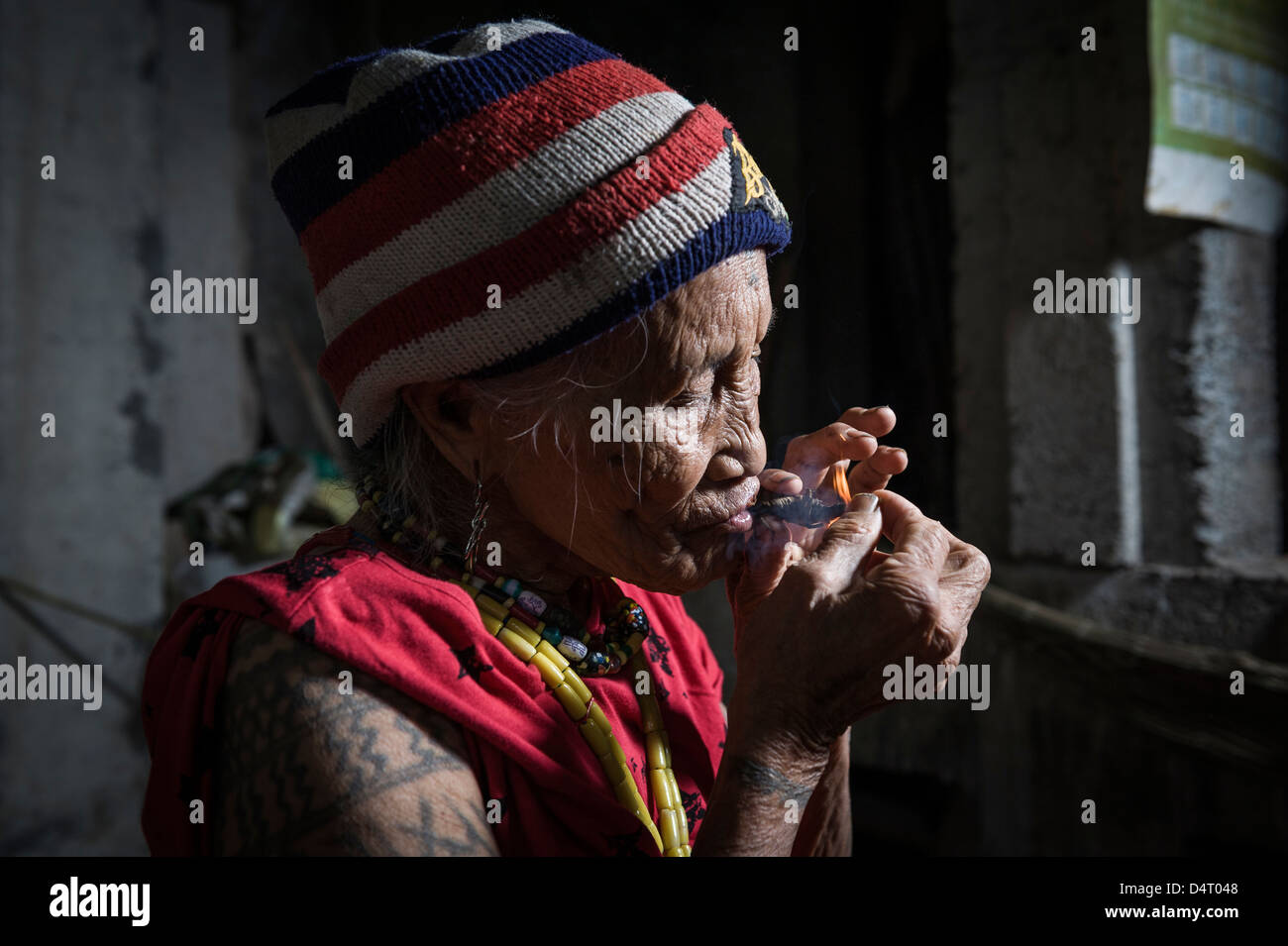 Alte einheimische Frau mit Tätowierungen, die Beleuchtung einer Zigarre, Kalinga, North Luzon, Philippinen, Asiens Stockfoto
