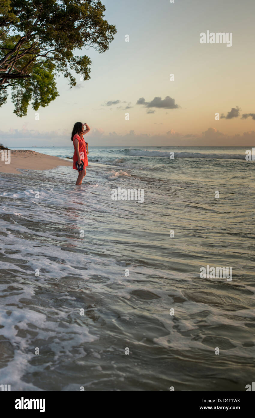 Eine Frau Spaziergänge am Strand bei Sonnenuntergang, in der Nähe von Holetown, Pfarrer von Saint James, Barbados Stockfoto