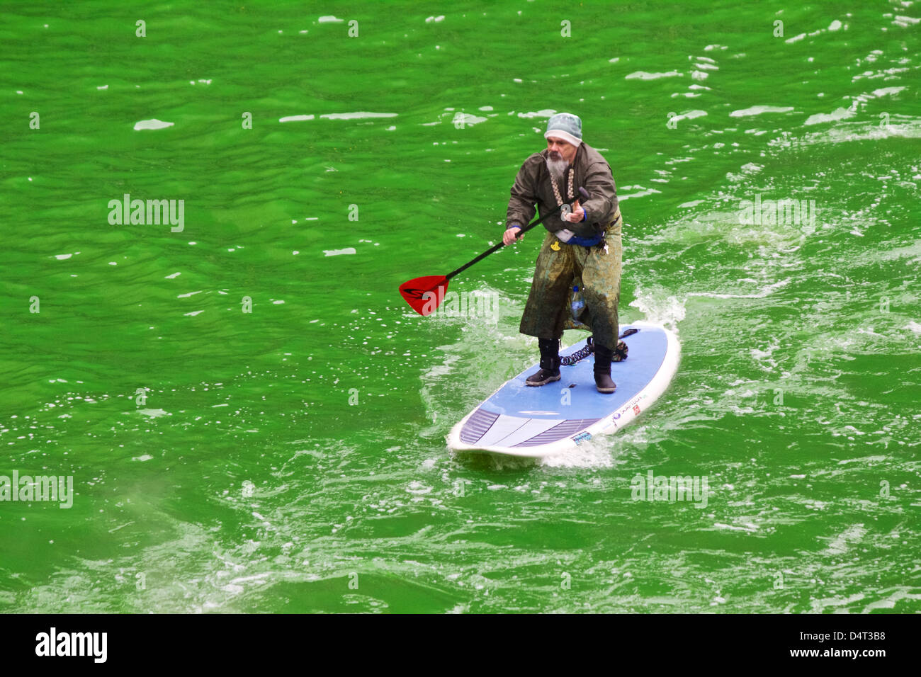 Ungewöhnlich gekleidet Mann ein Surfbrett auf dem Chicago River paddeln, für St. Patricks Day grün gefärbt Stockfoto