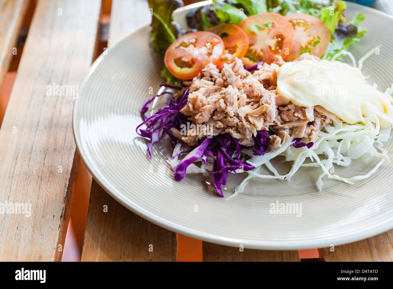 Thunfisch mit geschnittenen Kohlsalat auf Teller auf Holztisch Stockfoto