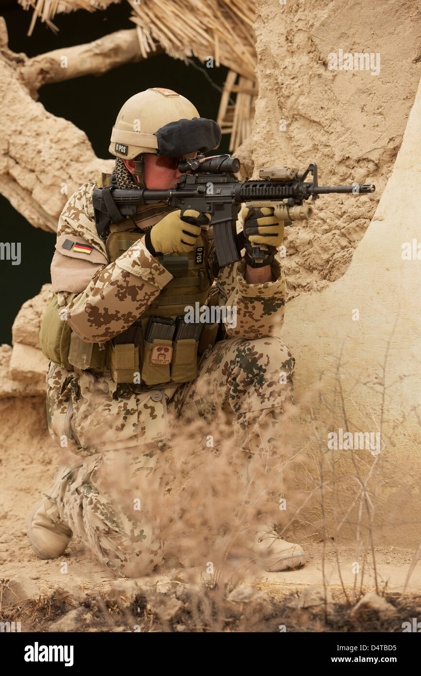 Ein Soldat der deutschen Armee bewaffnet mit einer M4 Karabiner Sturmgewehr in den Ruinen von einem afghanischen Gebäude. Stockfoto