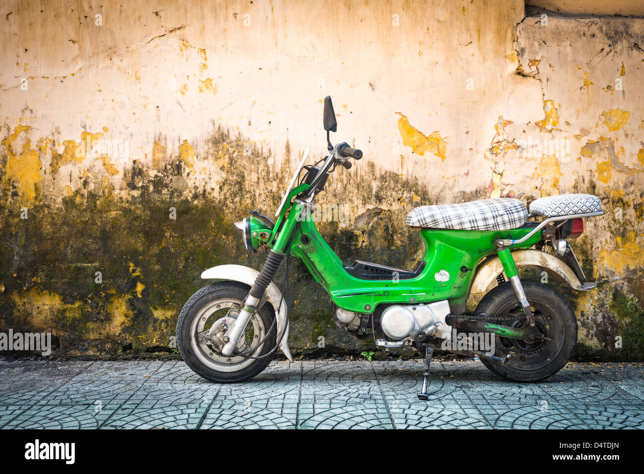 Grüne Roller gegen alte Haus. Verwitterte Wand als Hintergrund. Urban Street in Vietnam, Asien. Moped in verschimmelten geparkt stonewall. M Stockfoto