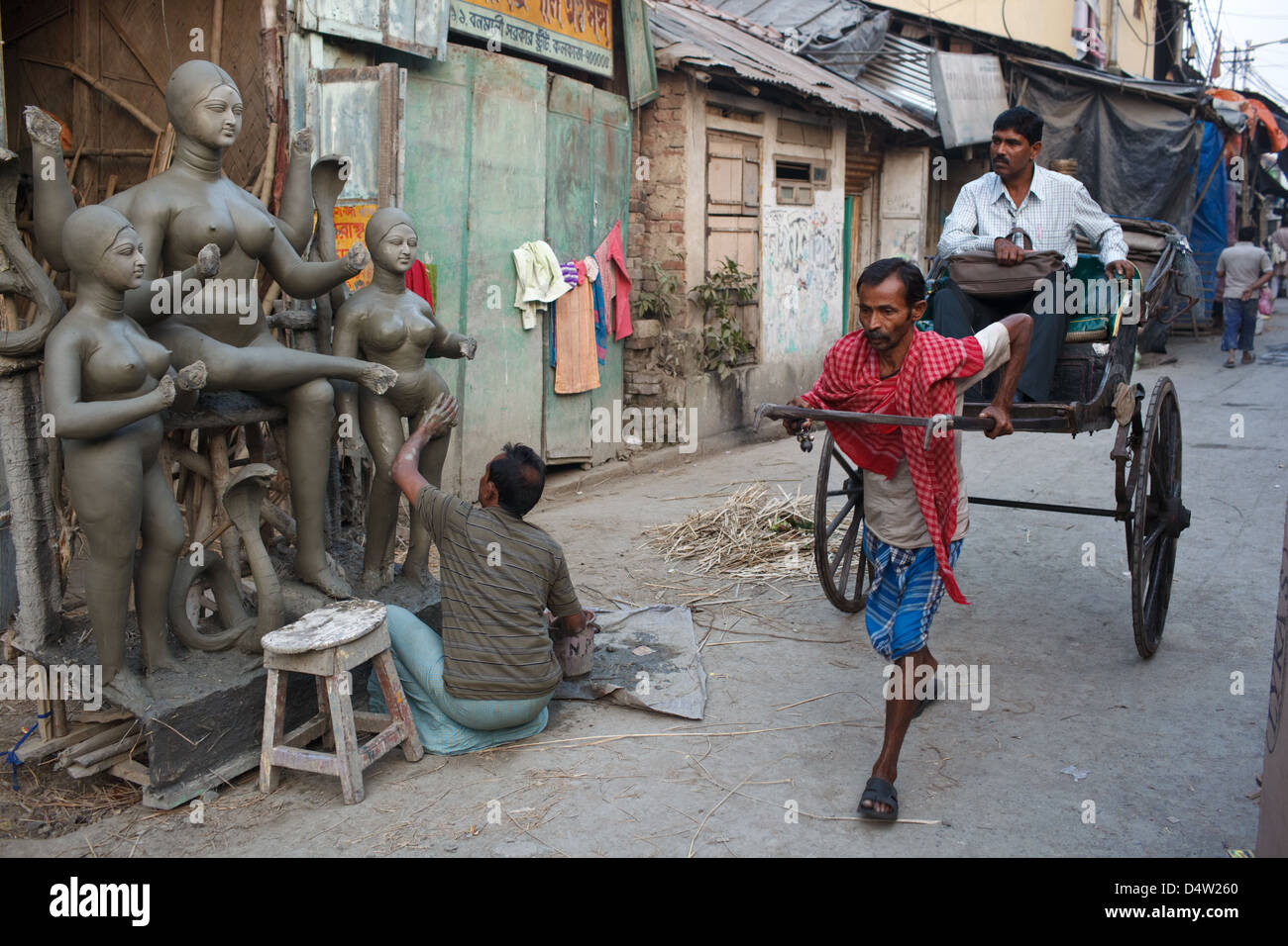 Ein Passagier in einer Rikscha Hand gezogen, im Stadtteil Kumartuli (Kumortuli) der traditionellen Töpfer in Kolkata (Kalkutta), Indien Stockfoto
