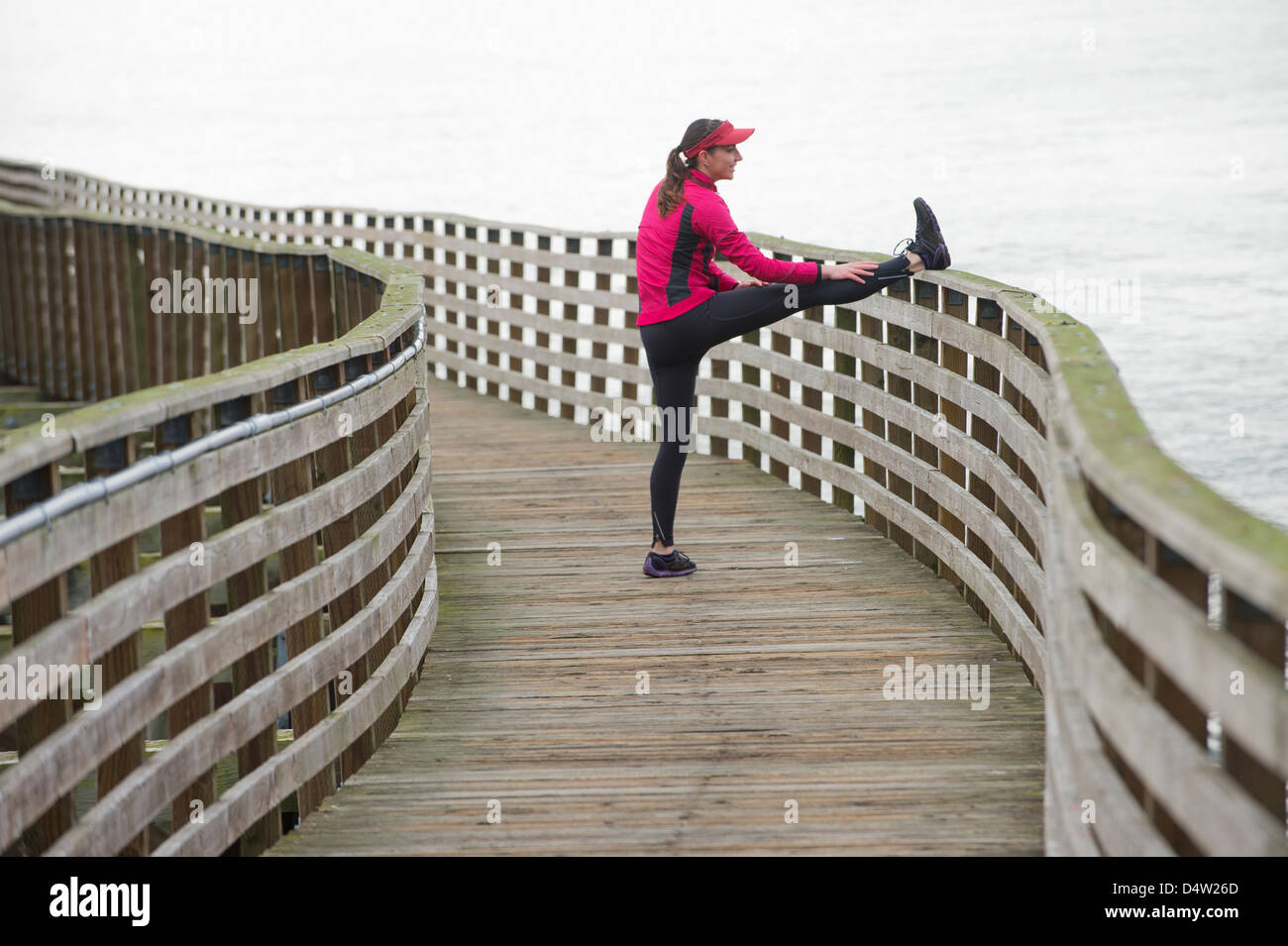 Läufer, die auf hölzernen Dock dehnen Stockfoto