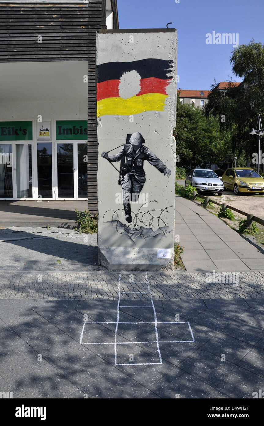 (dpa-DATEI) - ein Archivbild vom 16. September 2012 zeigt ein Reststück der Berliner Mauer mit einem Graffito, das das berühmte Bild eines DDR-Grenzschutzes aus dem Jahr 1961 zeigt, der über einen Stacheldrahtzaun in Berlin springt. Ein Hopp, der ihn vor dem Rest der Berliner Mauer auf dem Boden bemalt. Fotoarchiv für Zeitgeschichte () Stockfoto
