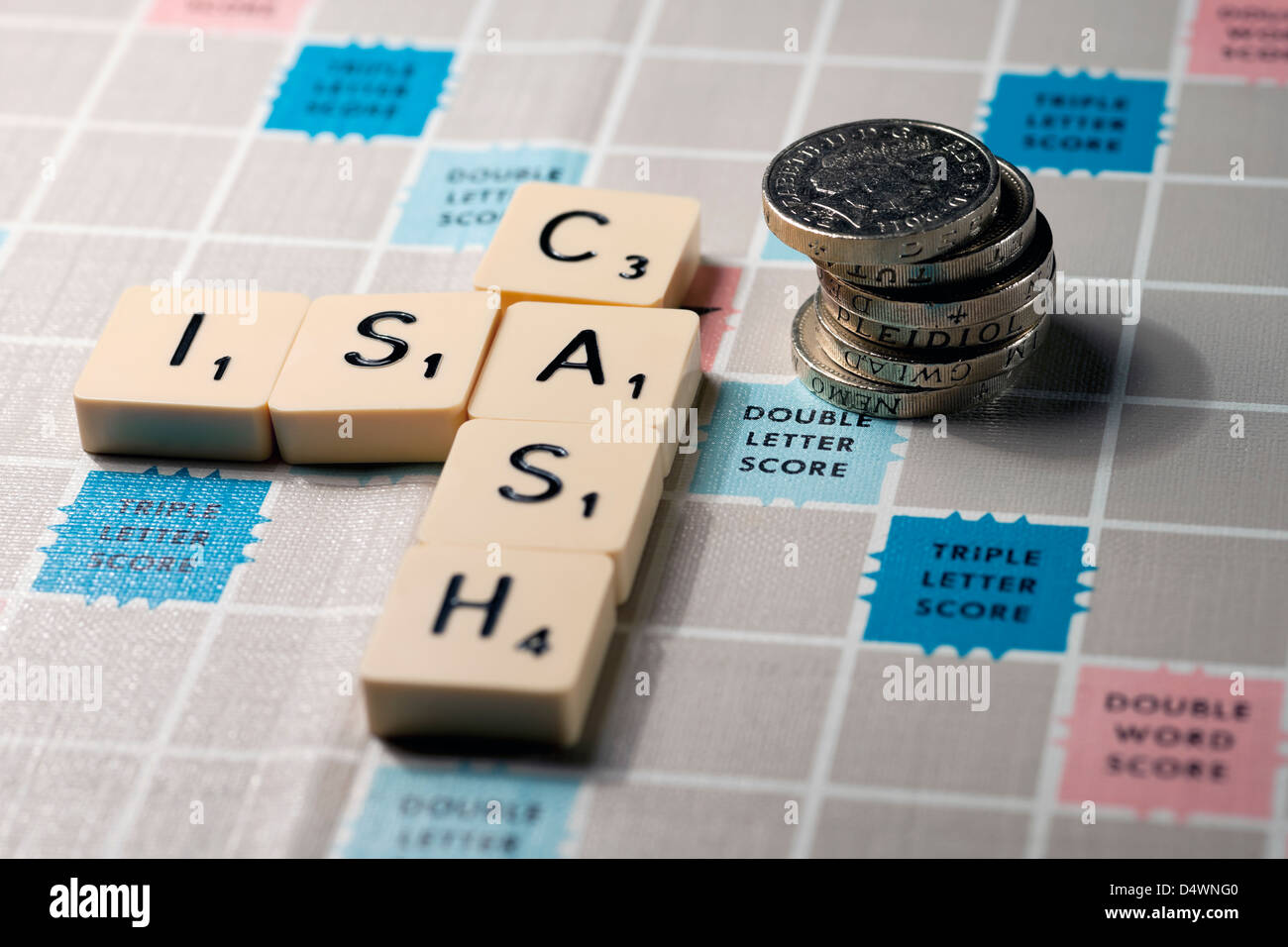 Nahaufnahme von Scrabble Board Wortwahl mit der Schreibweise Cash ISA und einem Stapel von englischen Pfund Münzen Geld Geschäftsfinanzierung Sparkonzept Stockfoto