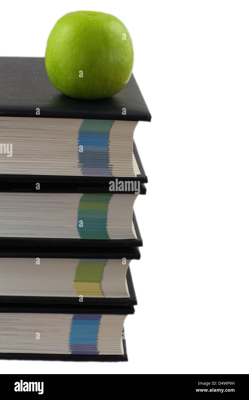 Stapel von Enzyklopädien mit grünem Apfel oben isoliert auf weiss Stockfoto
