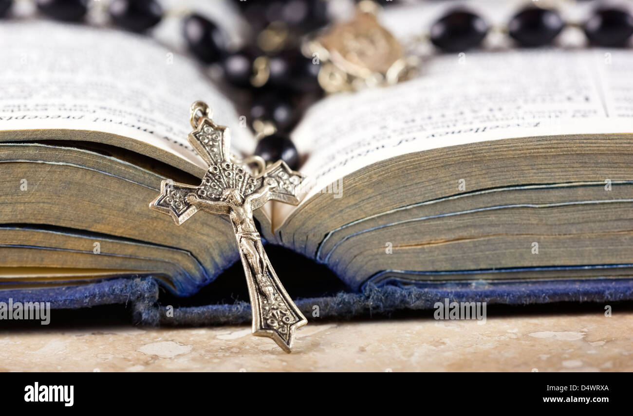 Rosenkranz und Kreuz liegend auf einer geöffneten Seite der Bibel. Stockfoto