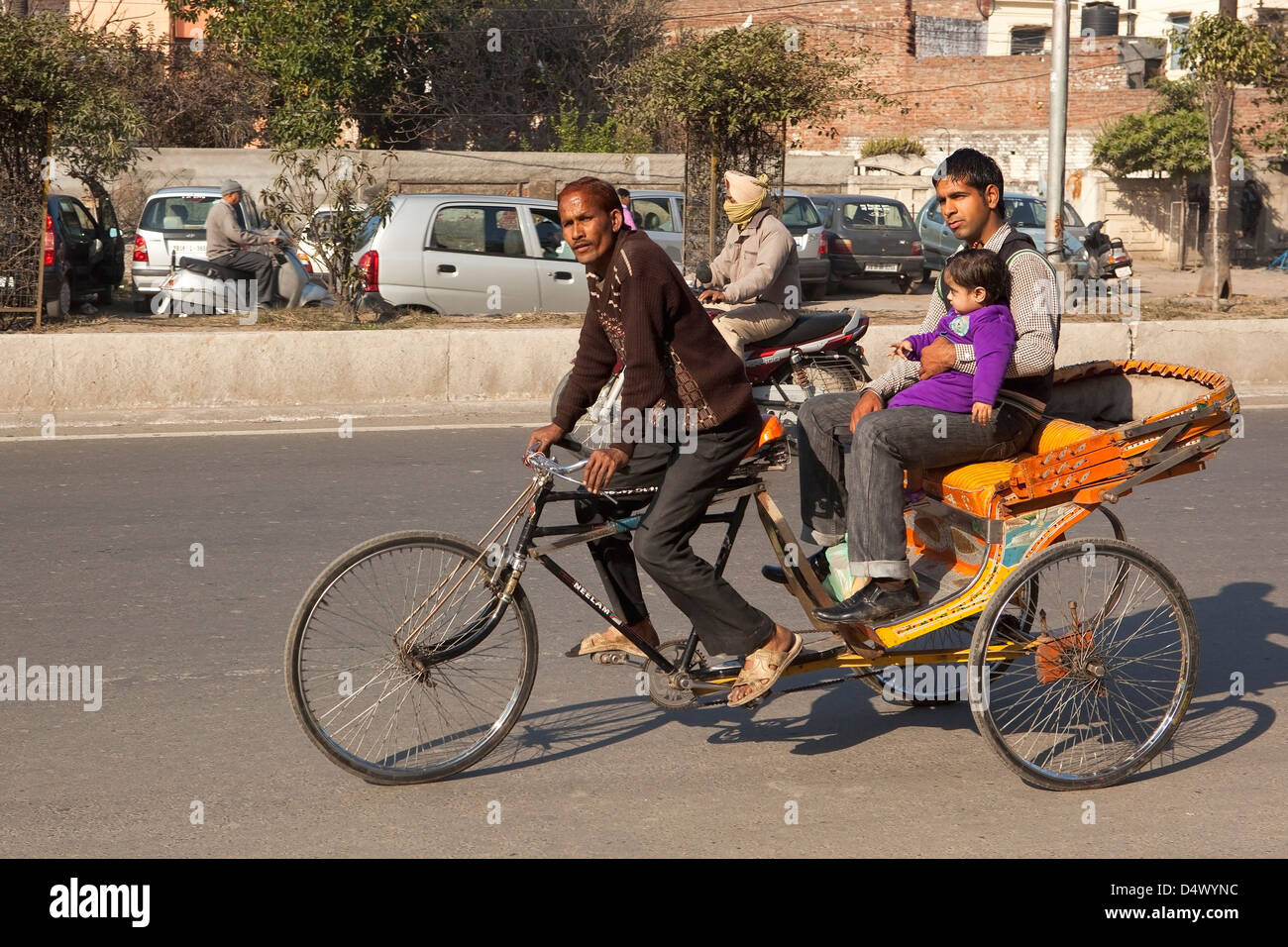 Ein Zyklus Rickshaw mit einem Mann und junge Kind als Passagiere auf den Straßen von Amritsar, Punjab, Indien. Stockfoto