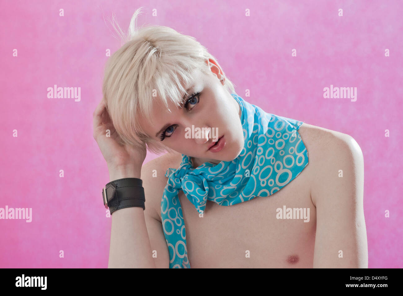 der hübsche junge Mann Homosexuell mit falschen Wimpern und Kosmetik auf einer Fläche auf einem rosa Hintergrund vermisst Stockfoto