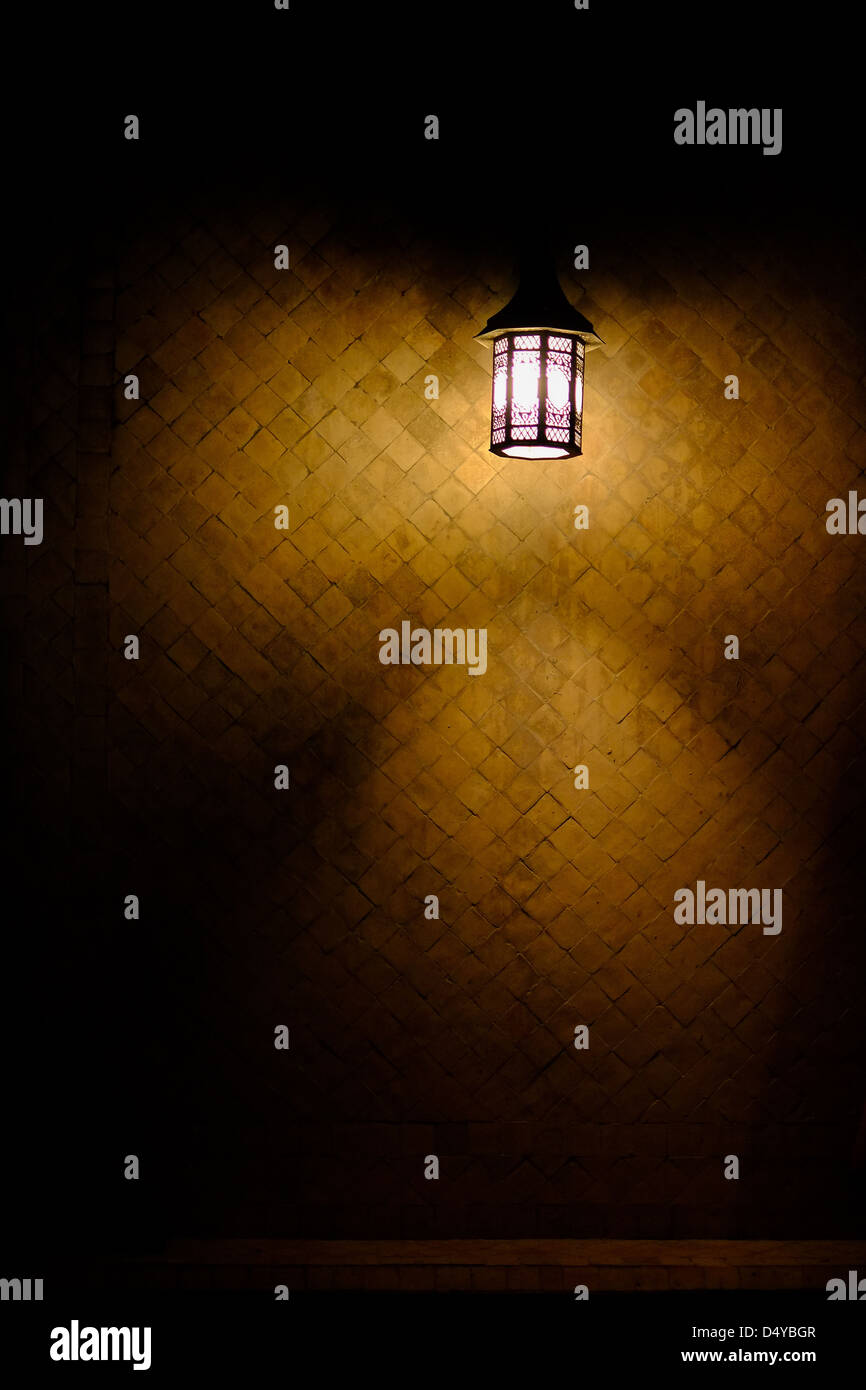 Eine Lampe in Fes, Marokko gegen eine traditionelle gelb gefliesten Wand hängen Stockfoto