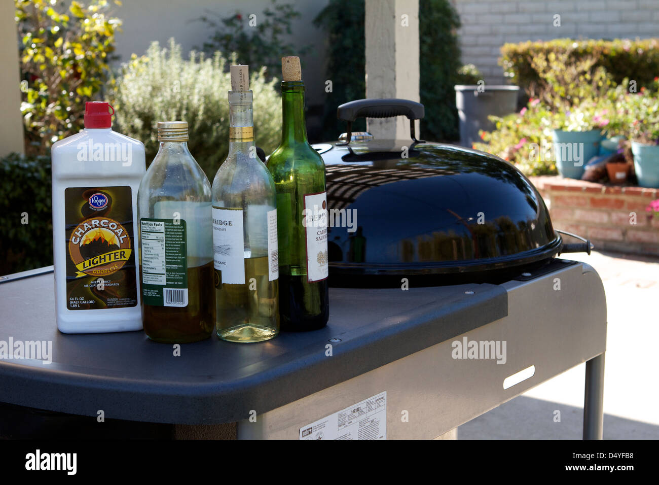 Ein Weber Grill im Freien in einem Garten mit Olivenöl Wein und leichter Flüssigkeit Stockfoto