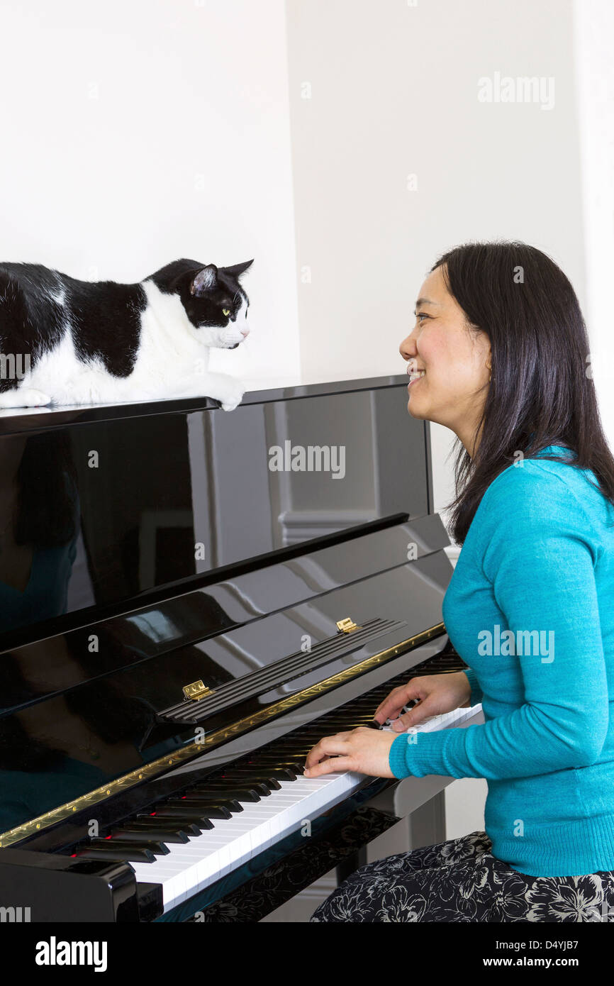 Vertikale Foto Reife Frau mit ihrer Katze auf Klavier sahen einander sitzend am Klavier Stockfoto