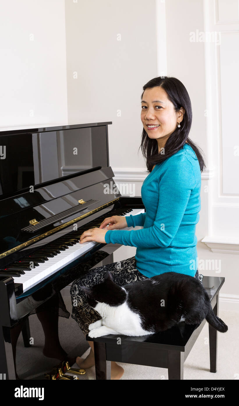 Vertikale Foto Reife Frau mit ihrer Katze an ihrer Seite sitzen am Klavier Stockfoto
