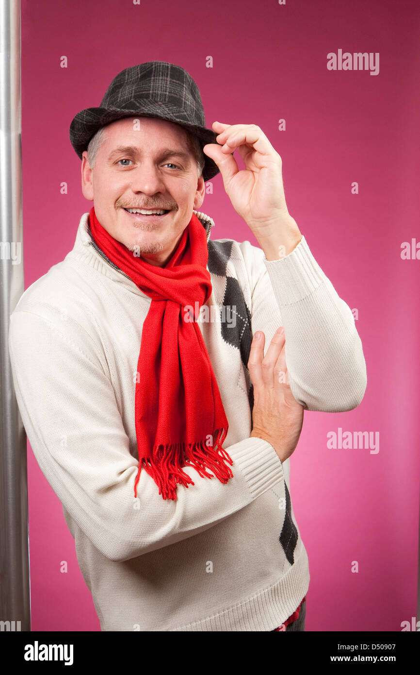 Porträt von lächelnder Mann trug einen Pullover und Schal Trinkgeld seinen Hut. Stockfoto