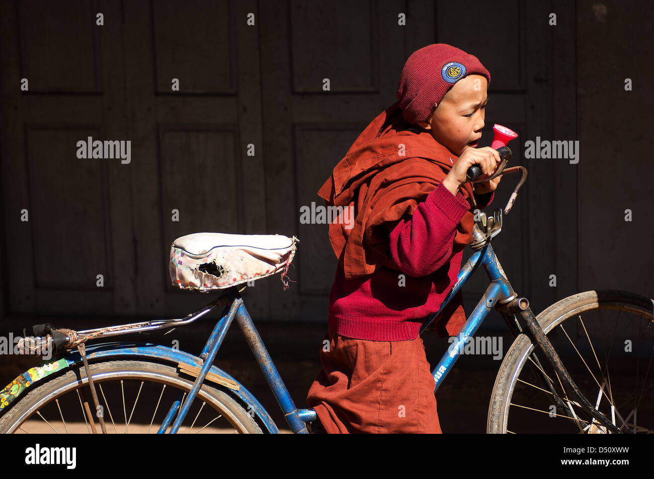 Ein junger Lehrling Mönch in einem Kloster in der Nähe von Hsipaw, Myanmar,  hat ein großes Fahrrad und ein sehr rosa Eistüte erworben Stockfotografie -  Alamy