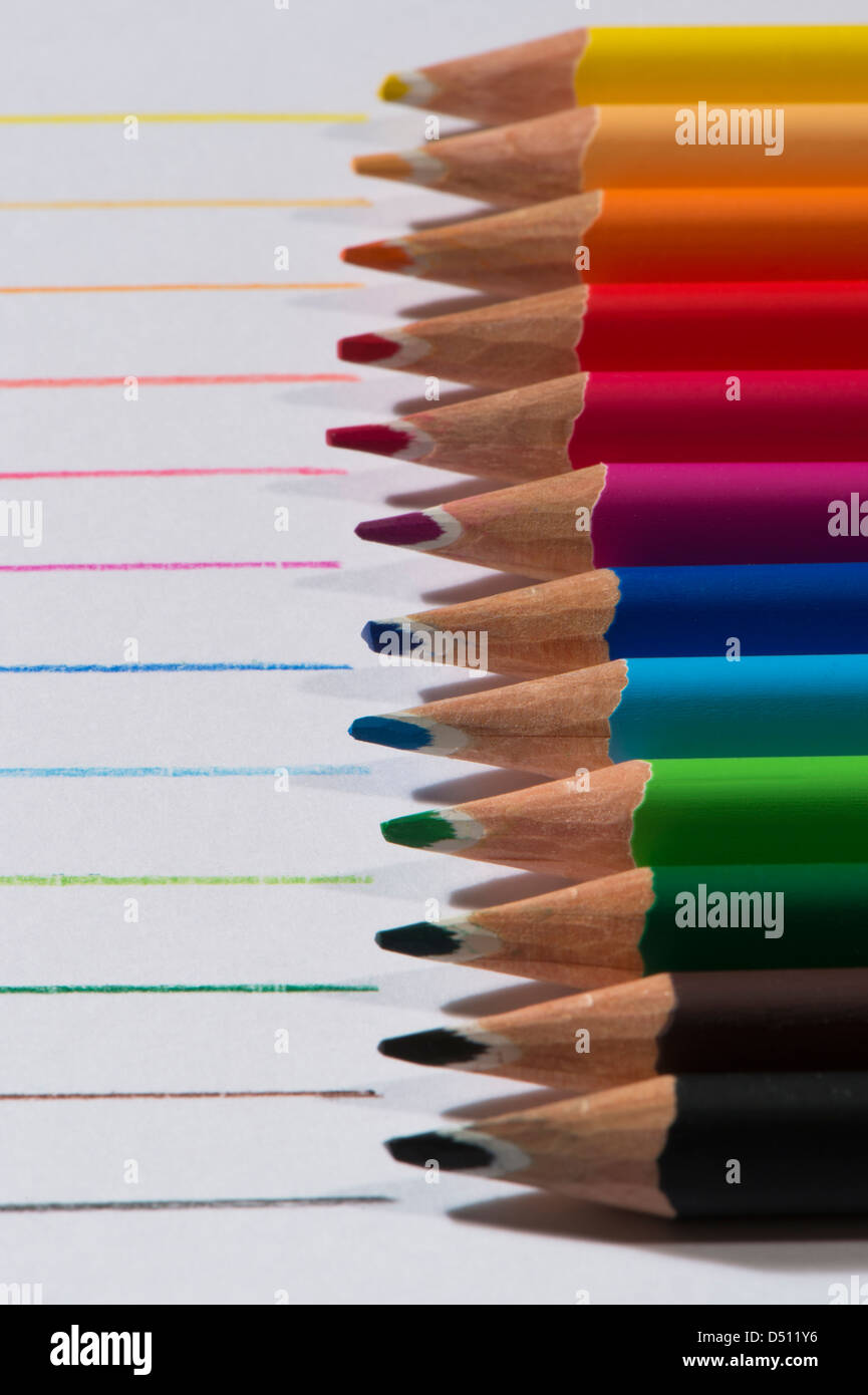 Close-up Detail von scharfen bunte Bleistiftzeichenstifte gelegt Seite an Seite auf weißem Papier Hintergrund von Zeilen in jeder Farbe - Yorkshire, England, UK. Stockfoto