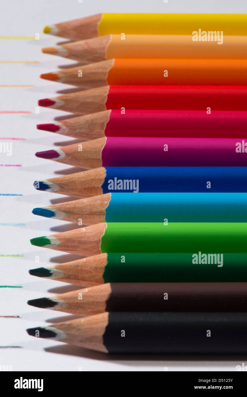 Close-up Detail von scharfen bunte Bleistiftzeichenstifte gelegt Seite an Seite auf weißem Papier Hintergrund von Zeilen in jeder Farbe - Yorkshire, England, UK. Stockfoto
