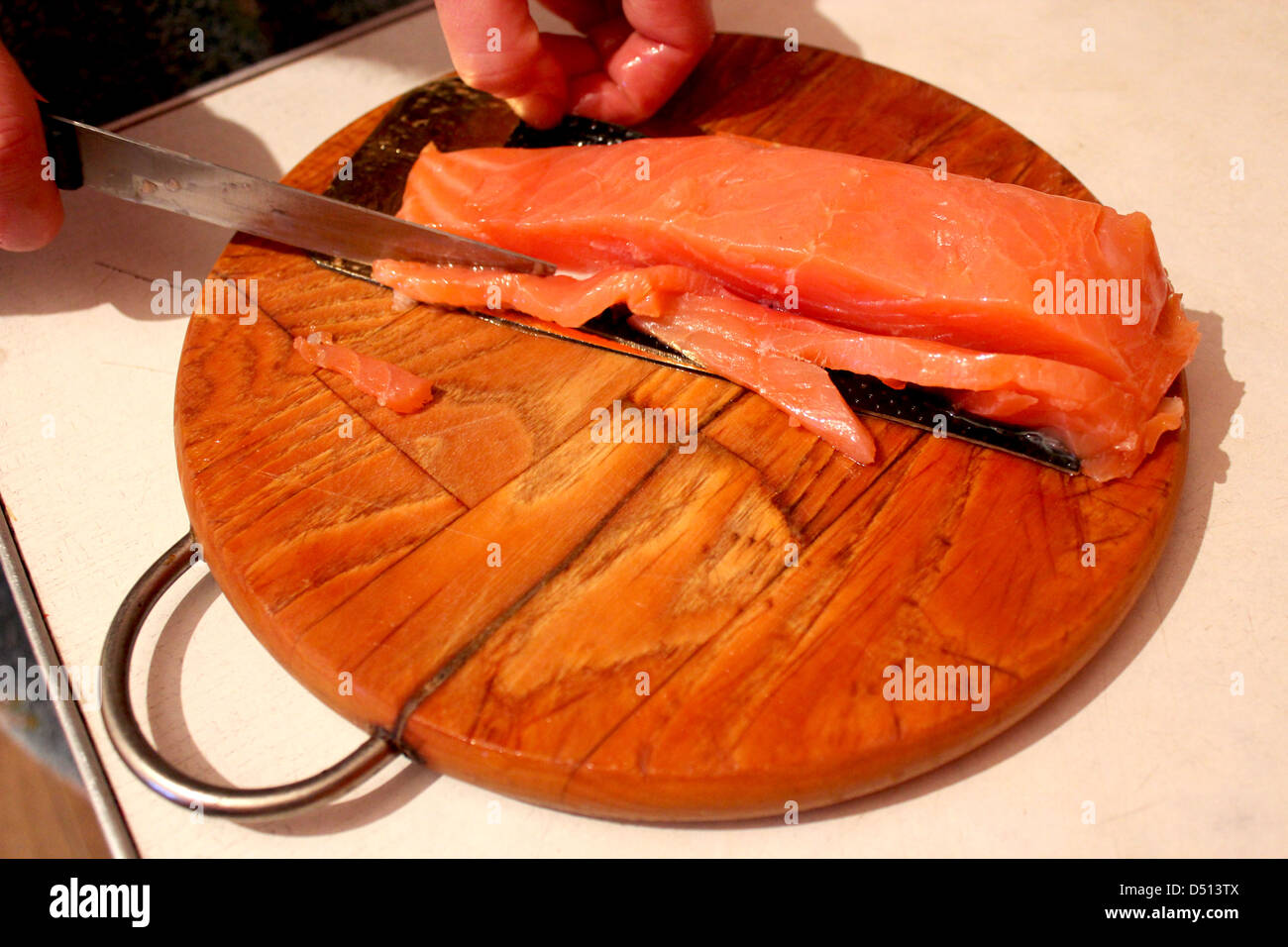 Bild von Hand schneidet Scheiben von roter Fisch Stockfoto