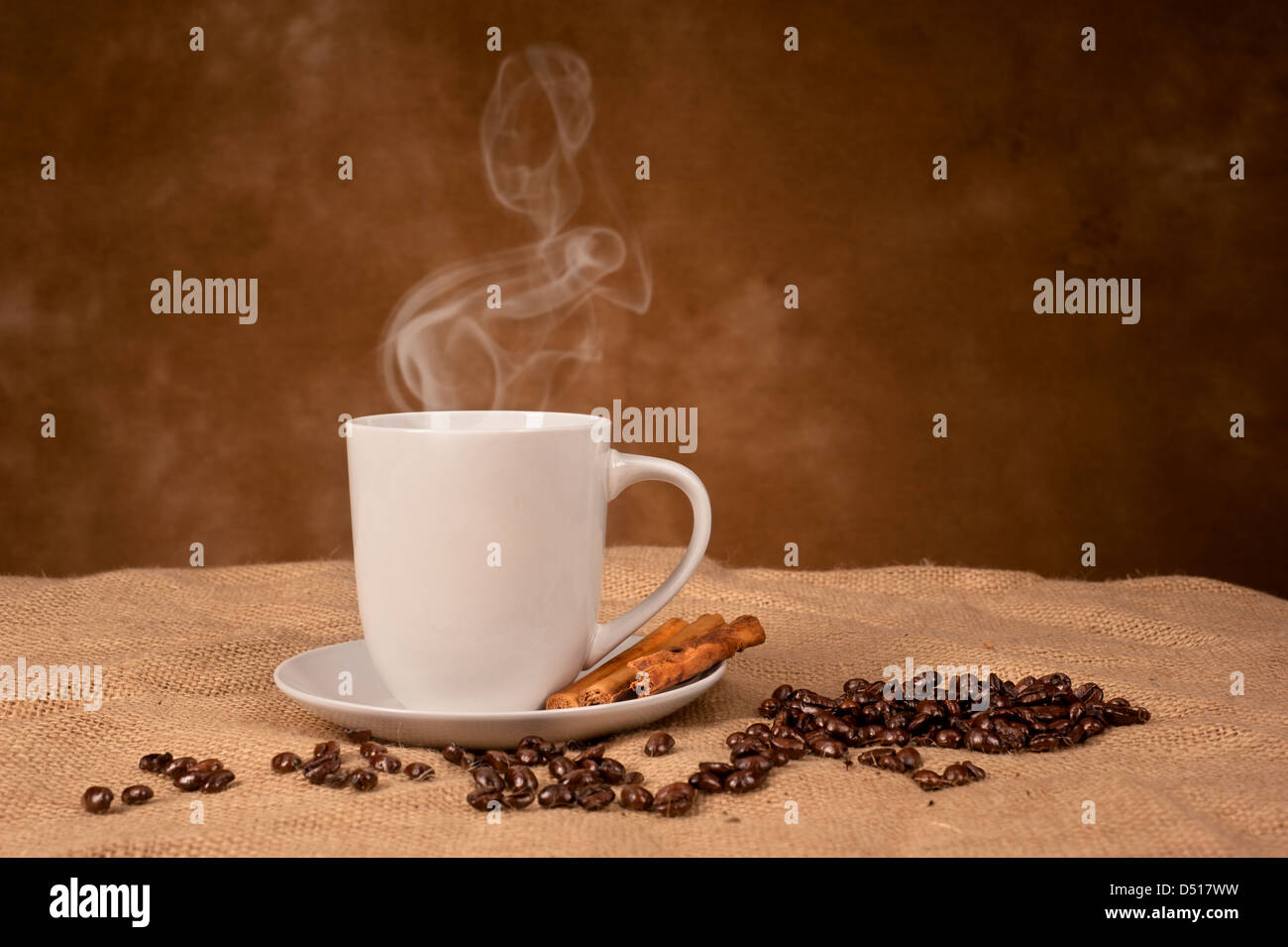 Einen heißer, dampfender Kaffee trinken mit Zimtstangen auf Sackleinen mit Platz für Kopie auf dem Hintergrund. Stockfoto