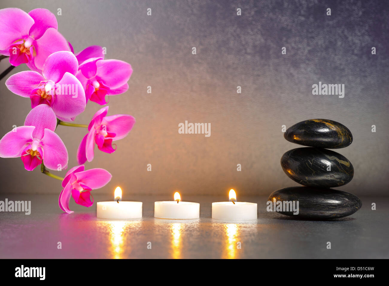 ZEN mit Kerze, gestapelten Steinen und Orchidee Blume Stockfoto