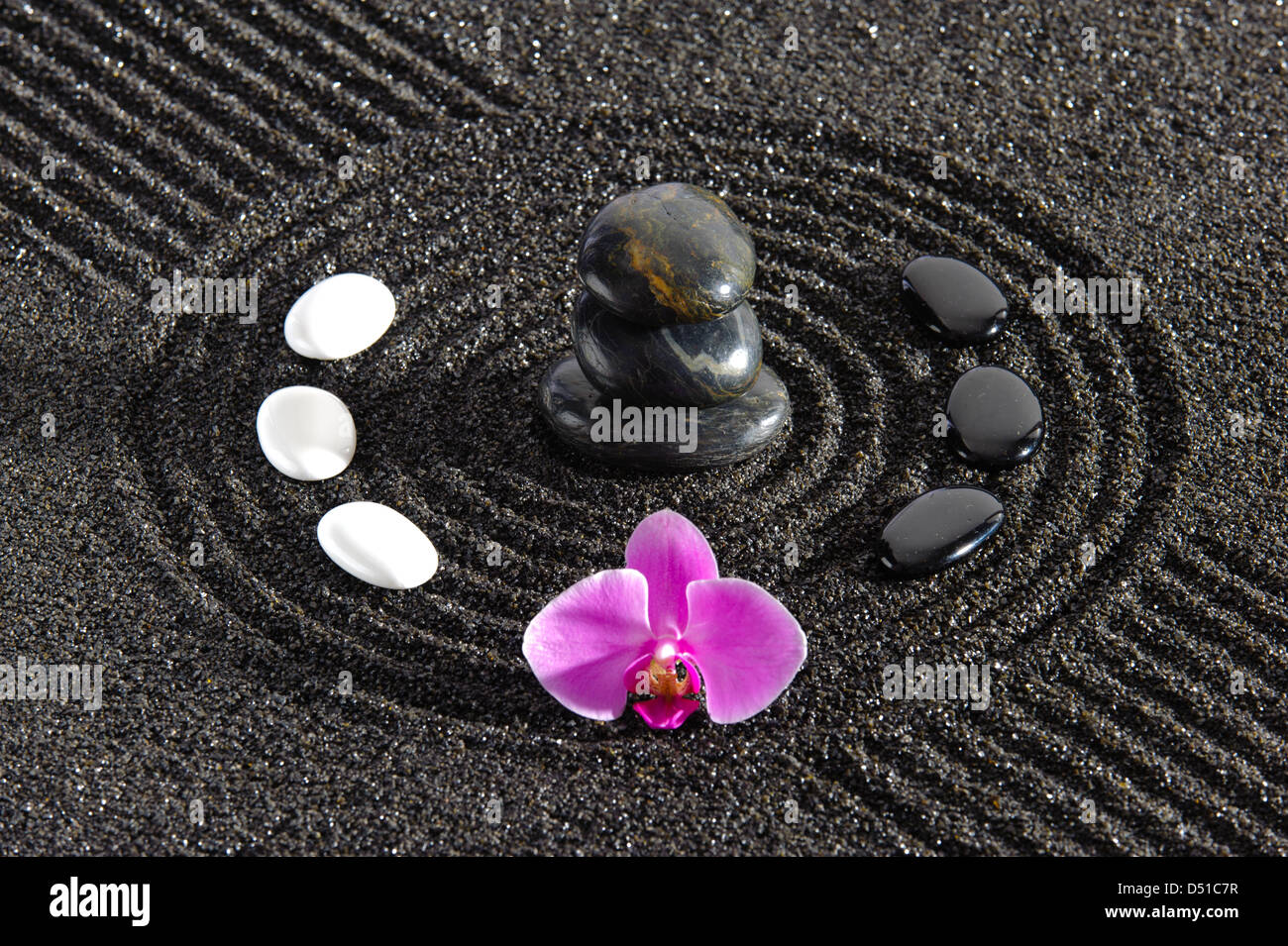 Japanischer ZEN-Garten im Sand mit gestapelten Steinen und Orchidee Blume Stockfoto