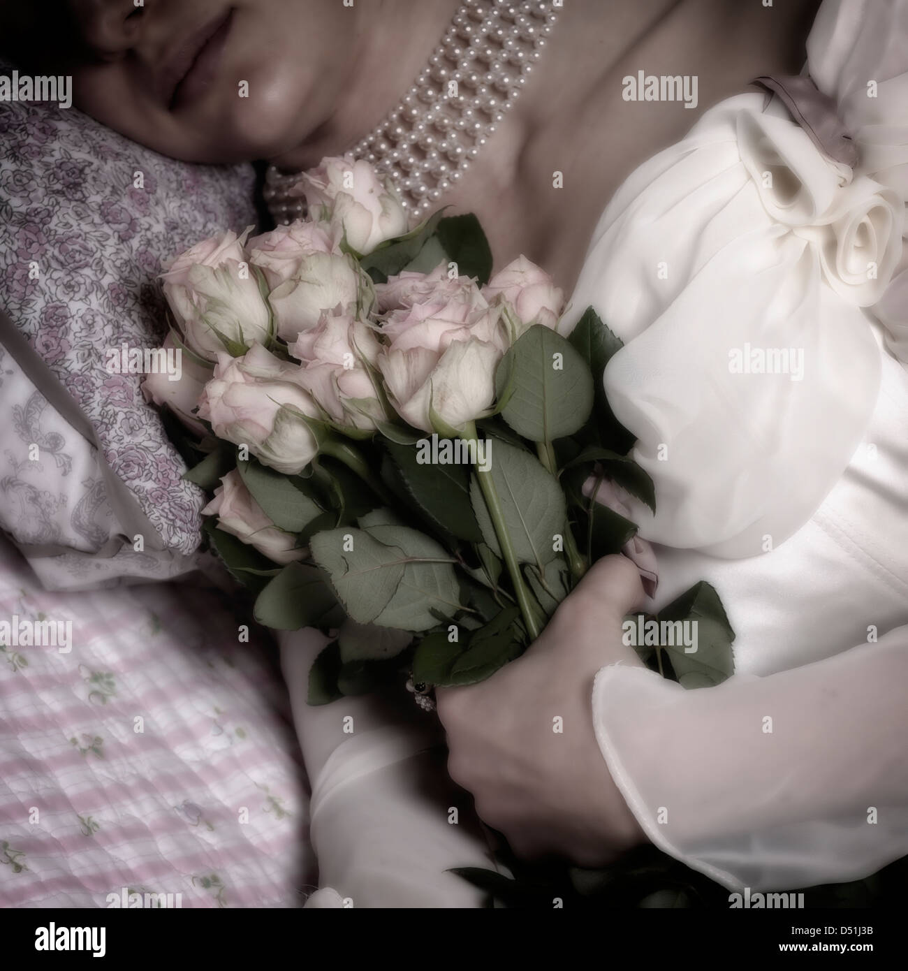 eine Frau im Bett mit einem Bouquet von rosa Rosen Stockfoto