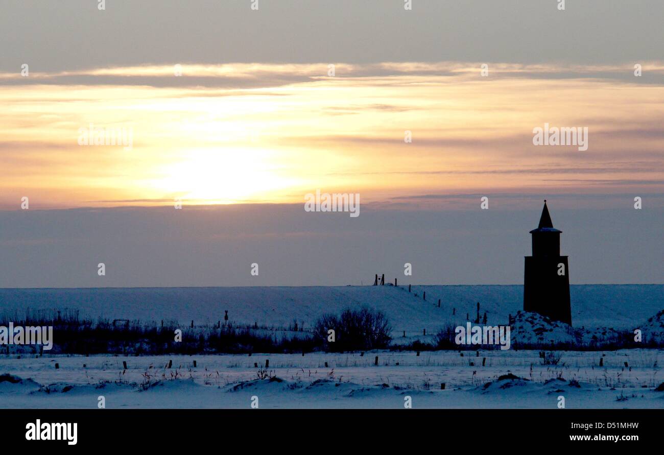die Sonne geht neben dem Leuchtturm über den Strand in Dagebuell, Deutschland, 28. Dezember 2010. Keinen Schnee mehr hat für die nächsten Tage prognostiziert. Foto: Rainer Jensen Stockfoto