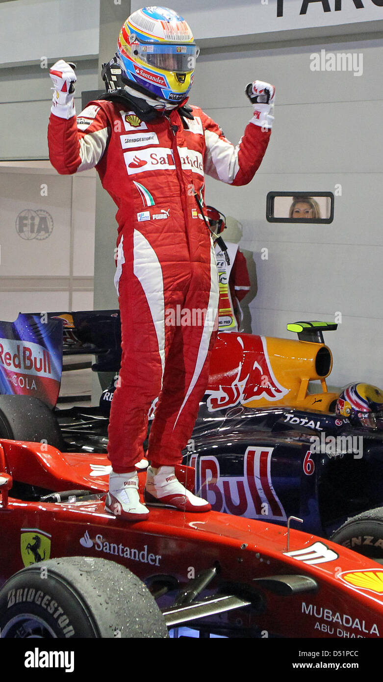 Spanischen Formel-1-Fahrer Fernando Alonso Ferrari-Team steht gekleidet in voller Montur auf der Motorhaube seines Rennwagens und Jubel nach dem Sieg der Grand Prix von Singapur auf dem Marina Bay Street Circuit in Singapur, 26. September 2010. Foto: Jan Woitas Stockfoto