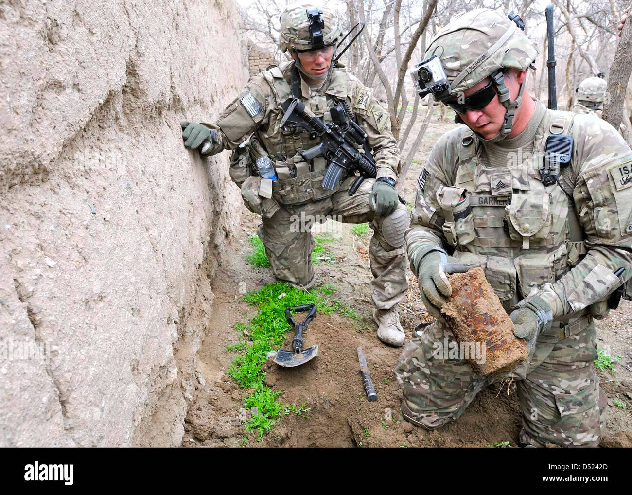 US-Armeesoldaten inspizieren ein Metallgehäuse, gefunden bei der Suche in einem Obstgarten während einer Patrouille in einem Dorf in der Nähe von Combat Outpost Jannat 22. Februar 2013 in der Provinz Kandahar, Afghanistan. Stockfoto