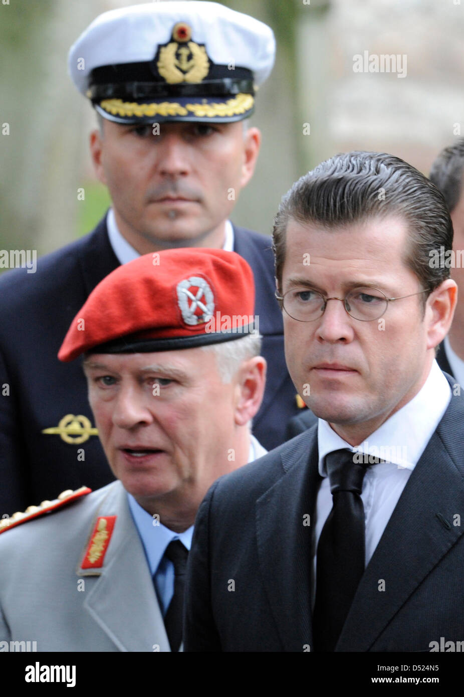 Nach der Trauerfeier watch German Defence Minister Karl-Theodor Zu Guttenberg (R) und Bundeswehr (Bundeswehr) Chef des Stabes Volker Wieker (unten L) als der Sarg von Oberfeldwebel Florian Pauli auf einem Leichenwagen außerhalb der St. Lamberti Kirche in Selsingen, Deutschland, 15. Oktober 2010 geladen wird. Die 26 Jahre alte deutsche Fallschirmjäger wurde durch einen Sprengsatz in Afghanist getötet. Stockfoto