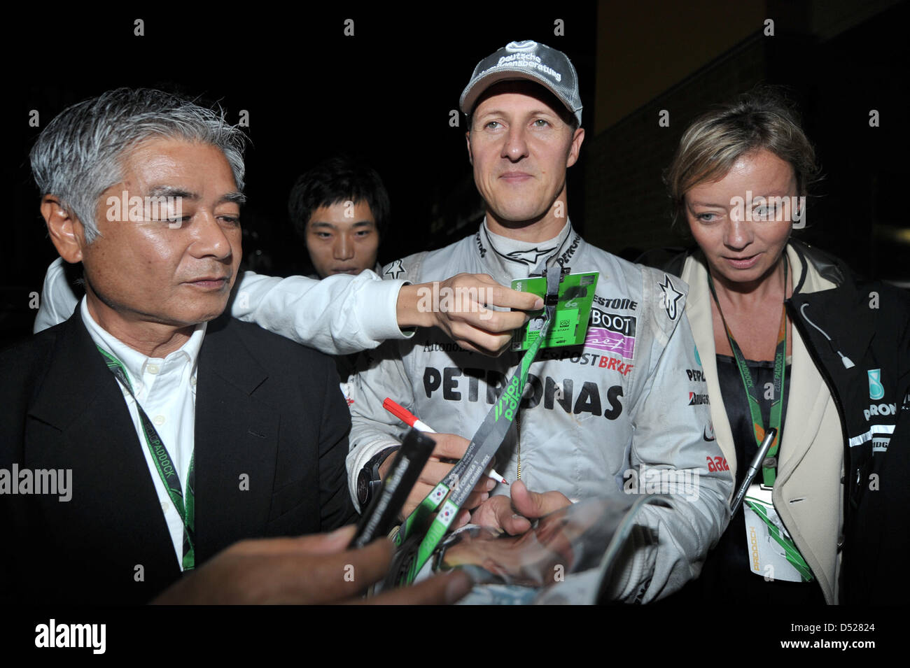 Deutscher Rennfahrer Michael Schumacher von Mercedes GP (M) ist umgeben von Autogramm Sammler nach dem Rennen auf Korea International Circuit in Yeongam, Südkorea, 24. Oktober 2010. Schumacher gewann den vierten Platz. Neben ihm geht sein Pressesprecher Sabine Kehm (R). Fernando Alonso Ferrari gewann das erste chaotische Formel1 Rennen in Korea vor Hamilton von McLaren und Massa von Ferrari. Stockfoto