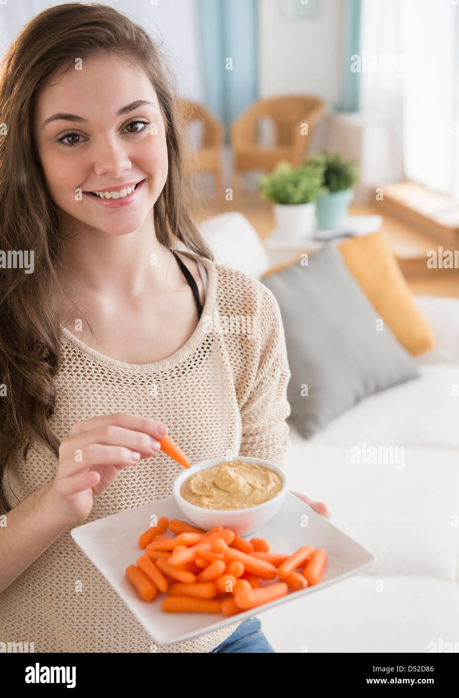 Hispanischen Mädchen essen Karotten und hummus Stockfoto
