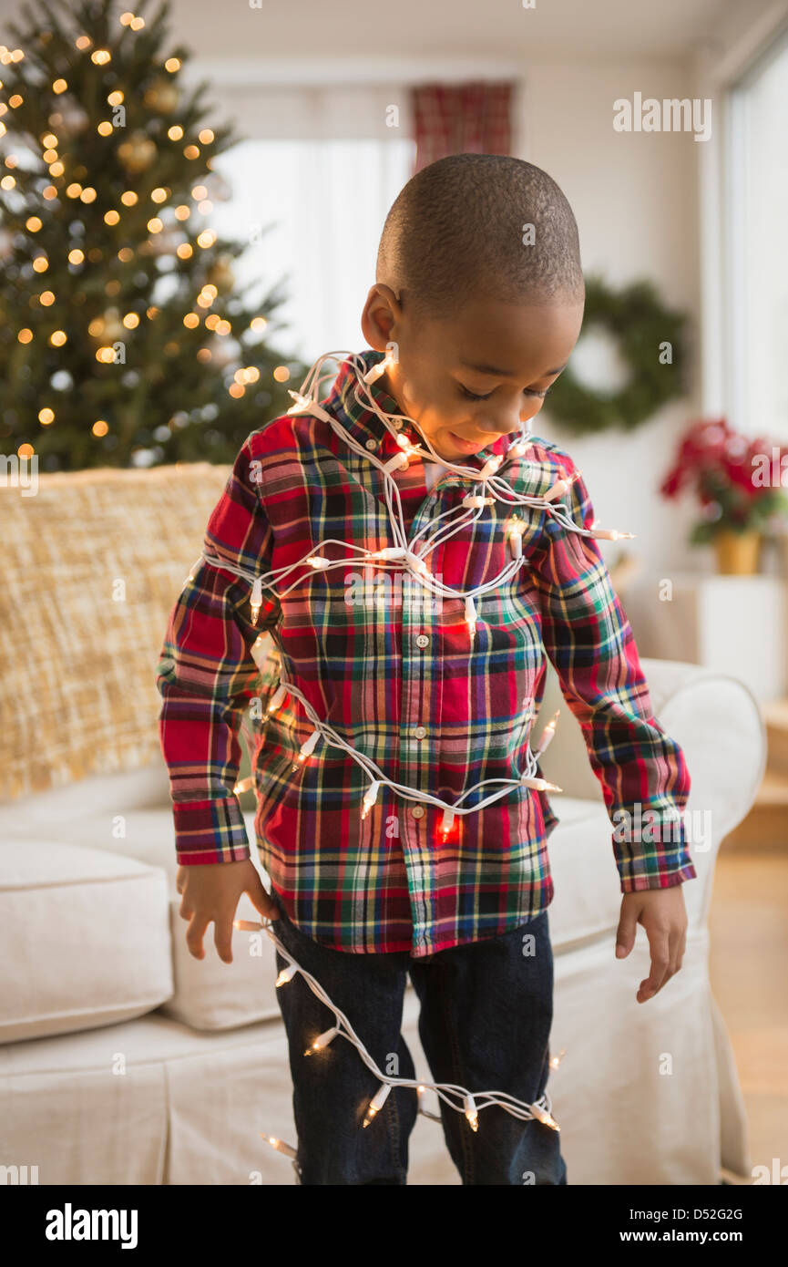 African American Boy, eingehüllt in Weihnachtsbeleuchtung Stockfoto