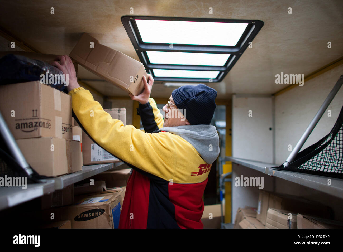 Ein Mitarbeiter von Deutsche Post DHL legt eine Paket in seinem Post-Bus an der ersten mechanischen Abgabestelle in Bochum, Deutschland, 20. März 2013. Es ist das zweite bundesweite System, das die Pakete automatisch liest und verteilt sie an den Transporter. Foto: Rolf Vennenbernd Stockfoto
