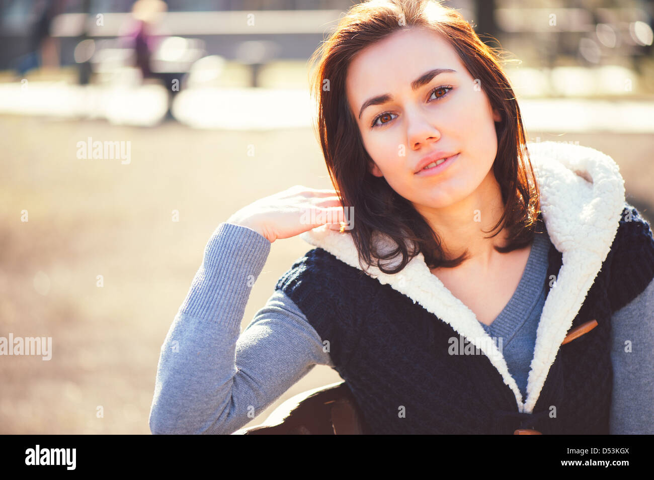 Porträt des jungen Mädchens im sonnigen Tag im Frühlingspark auf einer Bank sitzen Stockfoto