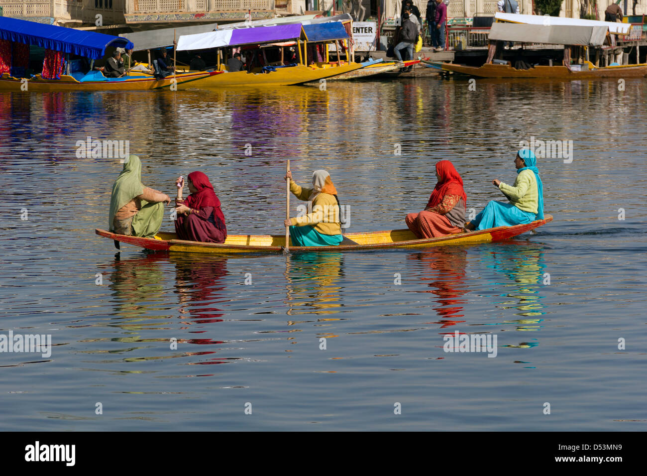 Damen Rudern ein klein und niedrig Holzboot auf dem Dal Lake mit dem Hintergrund der Hausboote Stockfoto