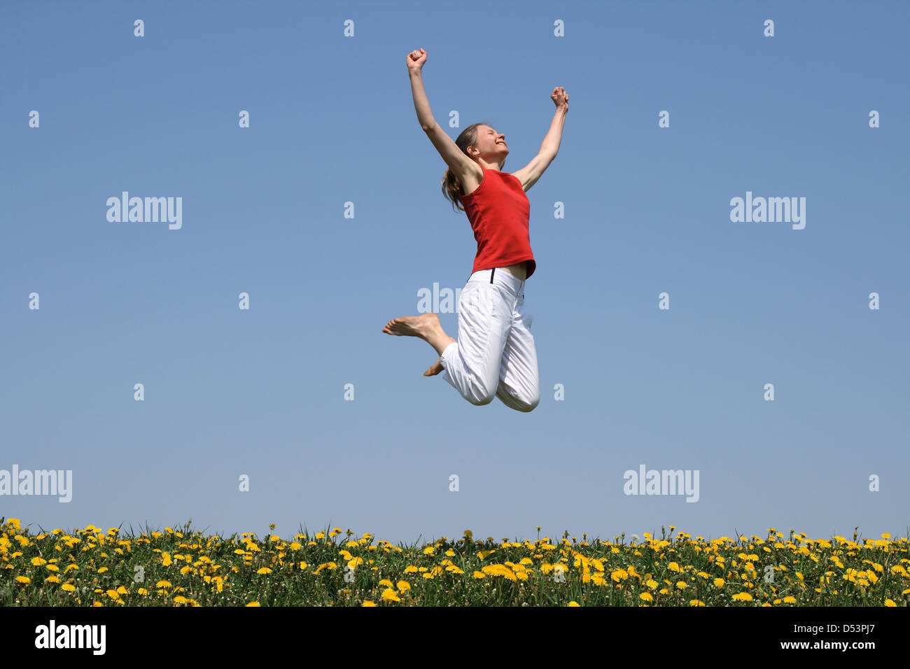 Ich bin der Sieger! Lächelnde junge Frau springt mit ihr in Freude erhobenen Armen. Stockfoto