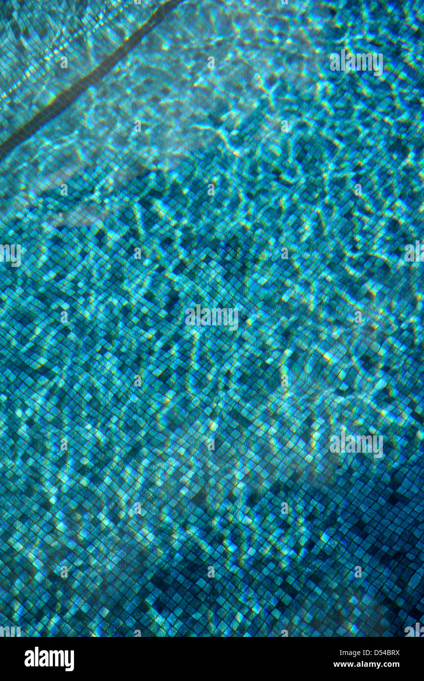 Plätschern des blauen Wassers im Swimmingpool mit Licht reflektiert Stockfoto