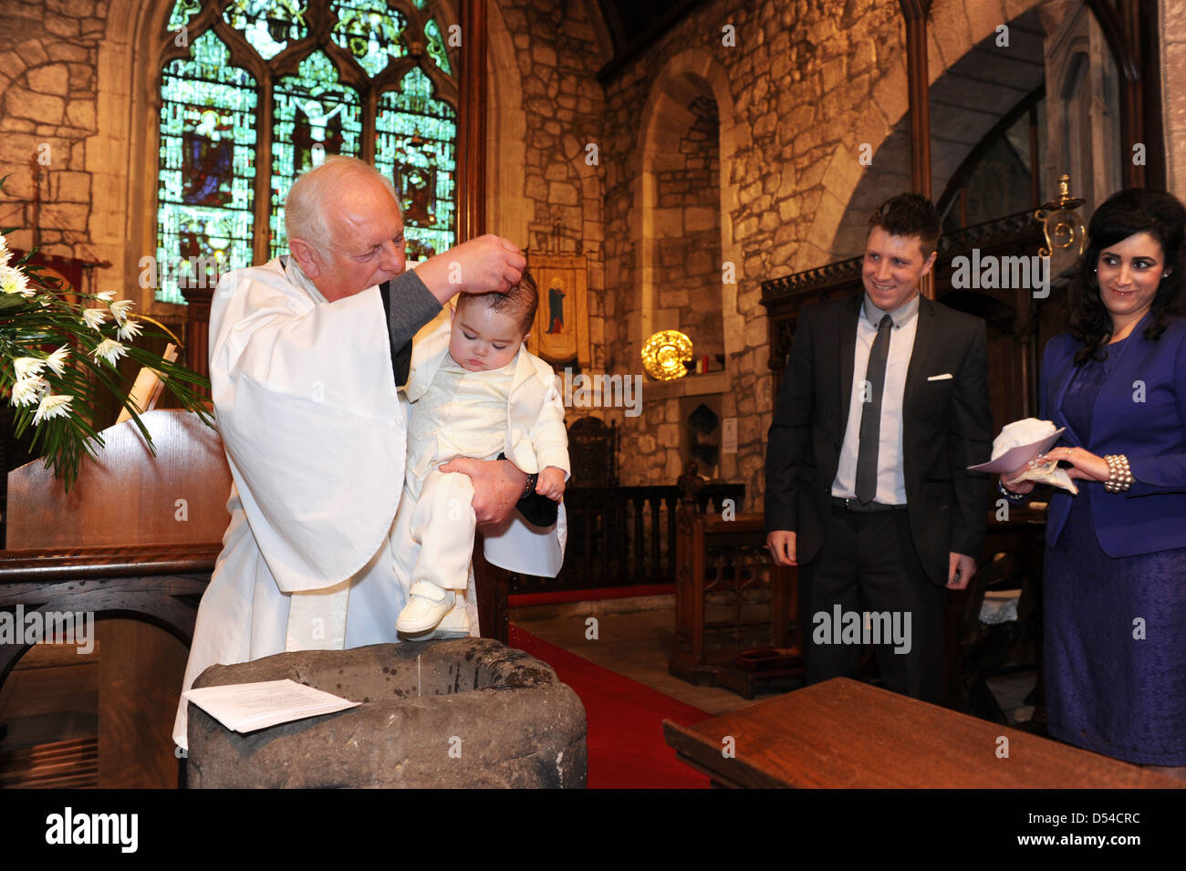 Kleines Kind, das von einem Vikar getauft und von den Eltern beobachtet wird England Großbritannien. Großbritannien England Taufe Kinder Kirche Familiendienst Taufe Stockfoto
