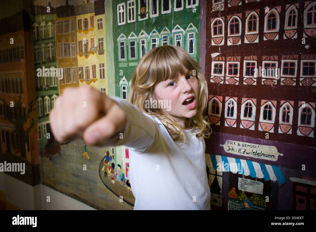 Berlin, Deutschland, spielt ein Mädchen Spiderman vor einer Wand gemalt mit Häusern Stockfoto