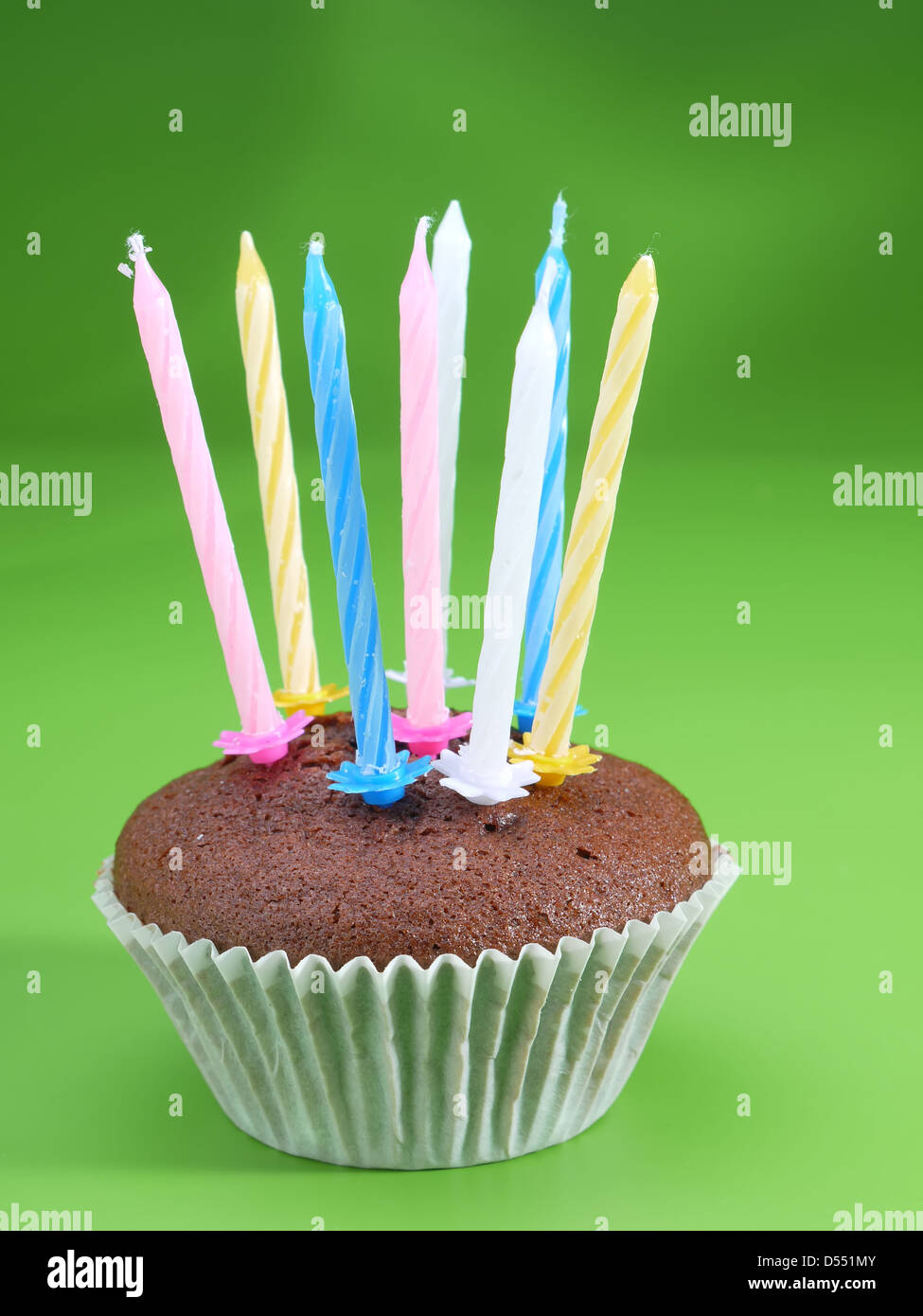 Schoko-Muffin mit acht Kerzen auf hellgrünem Hintergrund Stockfoto