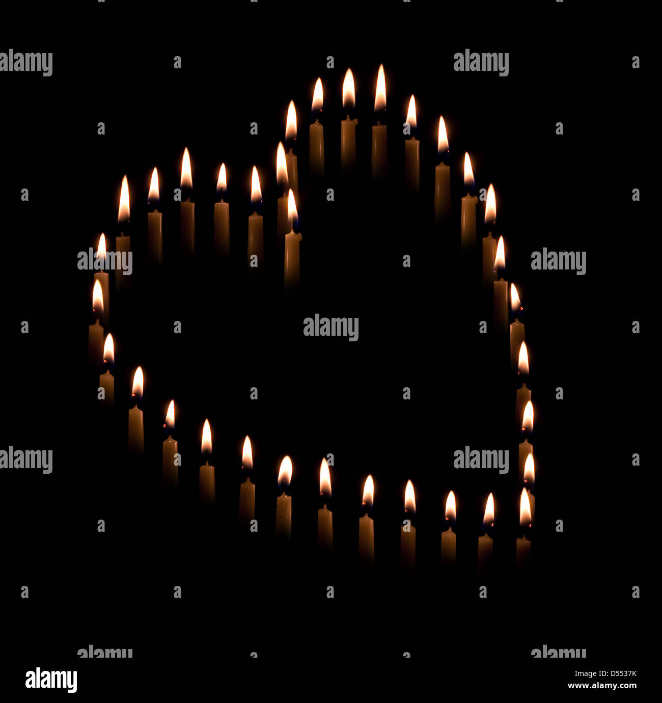Gruppe von Spitzkerzen bilden eine Kerze leichte Herzform mit schwarzem Hintergrund Stockfoto