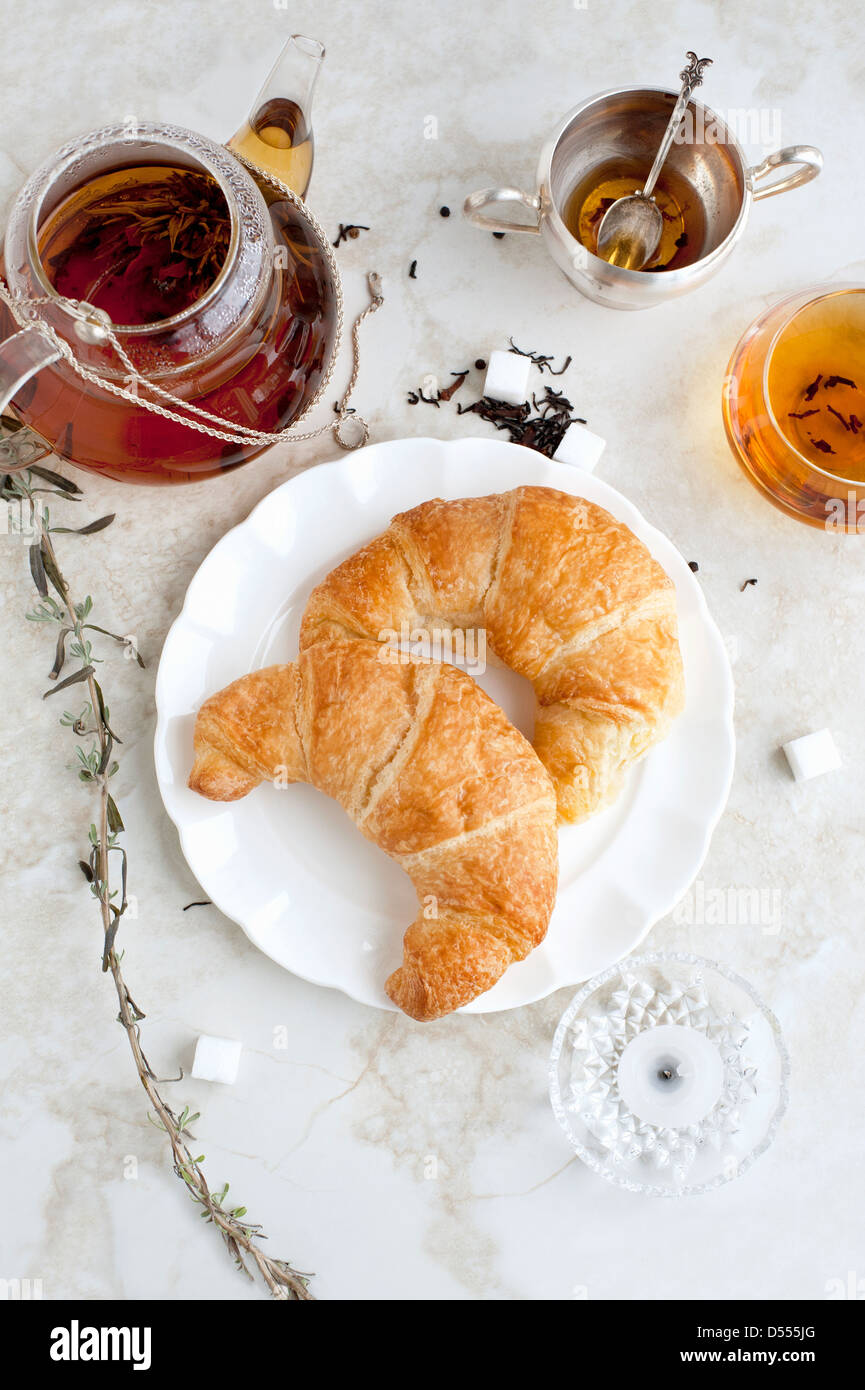 Croissants, Honig und Tee auf Tisch Stockfoto
