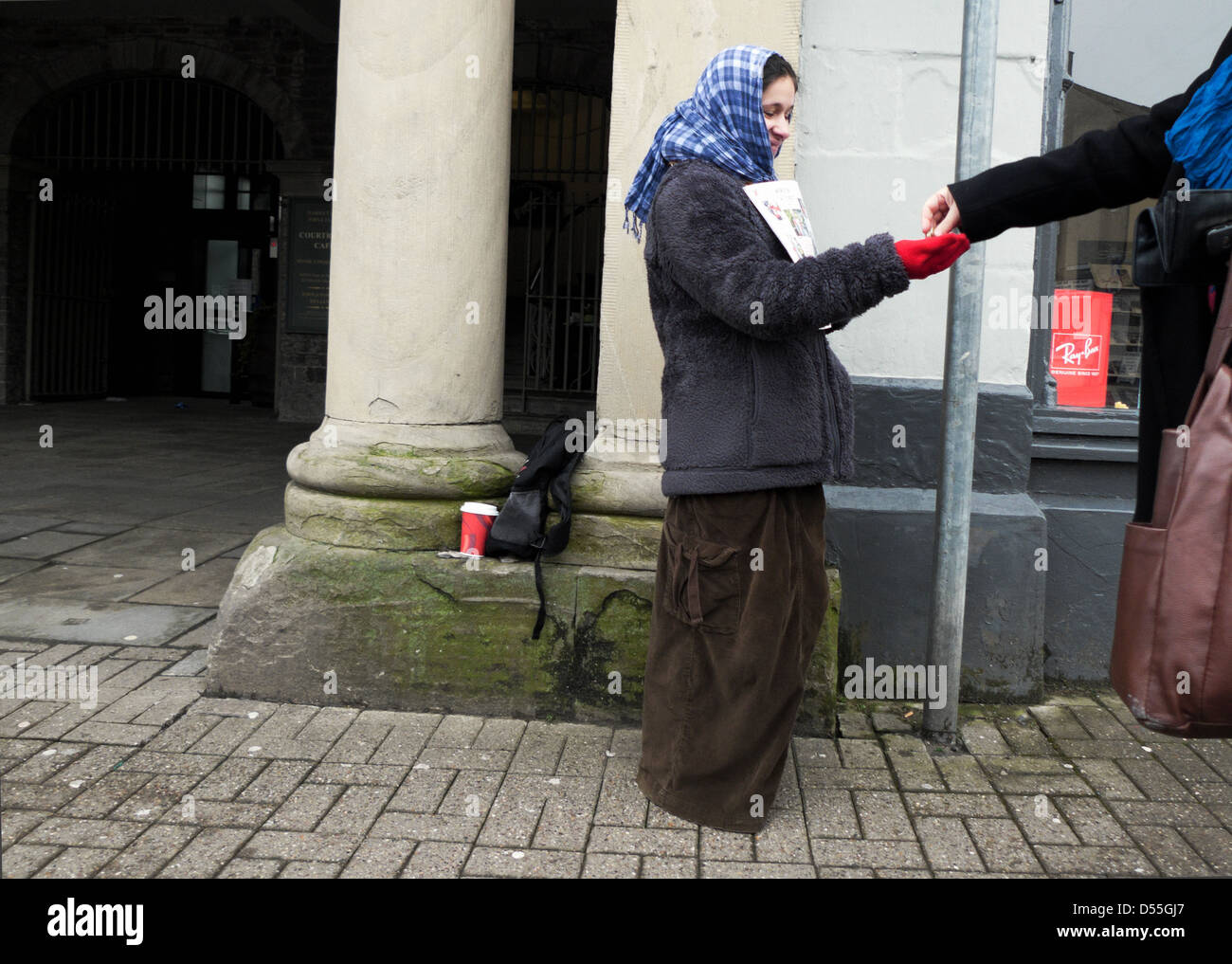 Eine junge Frau, die das Magazin Big Issue an einen verkauft Kunde zahlt Geldmünzen auf der Straße in Crickhowell Wales UK KATHY DEWITT Stockfoto